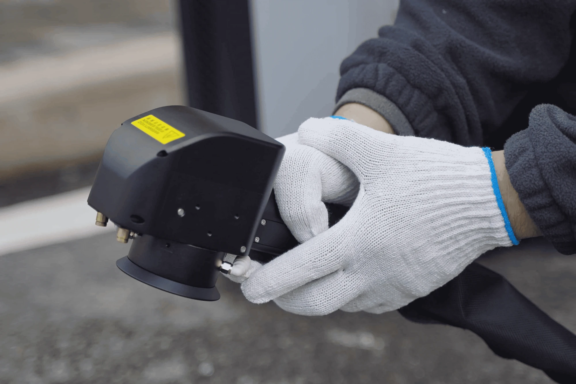 Operator guiding a pulsed laser head across a painted surface
